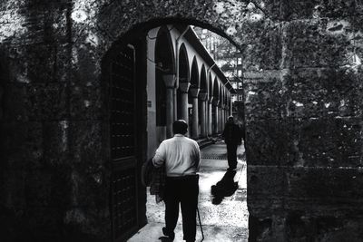 Rear view of man walking on alley amidst buildings