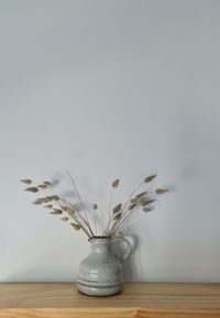 Close-up of vase on table against wall at home