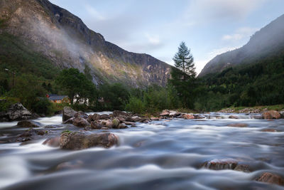 Surface level of stream by rocks against sky