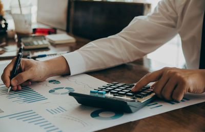 Midsection of businessman working on table