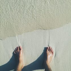 Low section of woman relaxing on sand at beach