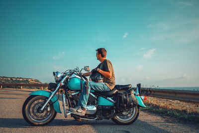 Man riding motorcycle on road against sky