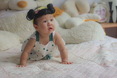 Cute baby girl lying on bed at home