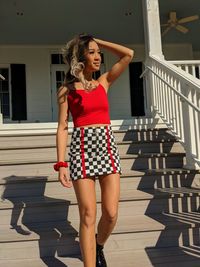 Full length portrait of young woman standing against railing