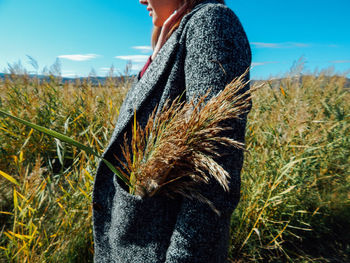 Midsection of woman with plant in pocket standing on land