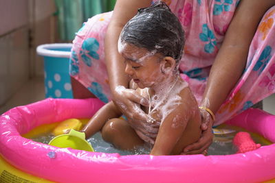 Midsection of a woman with girl sitting in water