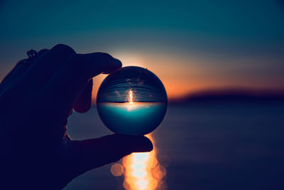 Hand holding lensball reflecting sunset at chambers bay, wa