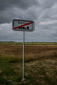 Information sign on field against sky