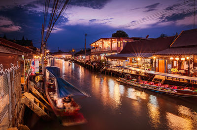 Illuminated boats moored in canal at night