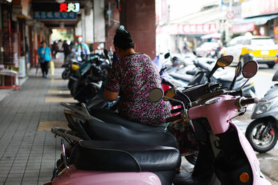 Rear view of woman sitting on motor scooter on street