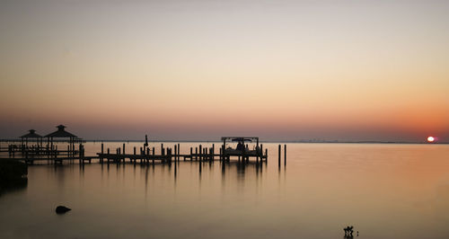 Pier on sea against clear sky during sunset