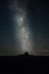 Low angle view of silhouette landscape against star field at night