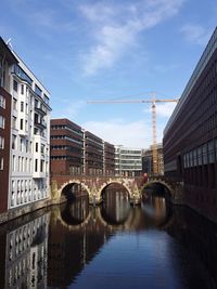 Bridge over river in city against sky