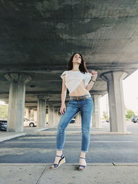 Low angle portrait of young woman holding top while standing at parking lot