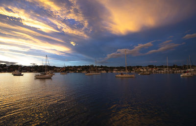 Sailboats in sea at sunset