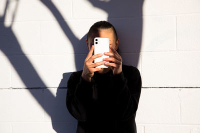 Woman looking at cell phone with tree shadow