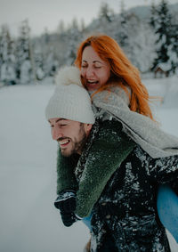 Young woman smiling in snow covered tree during winter