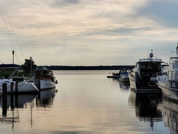 Sailboats moored at harbor against sky during sunset