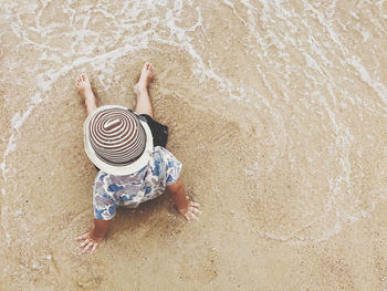Directly above shot of child siting on sand at beach