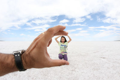 Hand pretending to hold a cheerful girl on landscape