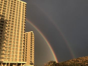 Low angle view of rainbow over buildings against sky