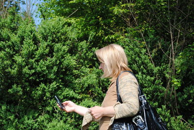 Side view of woman using mobile phone in forest