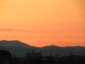 Scenic view of silhouette mountains against orange sky