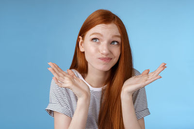 Portrait of young woman against blue background