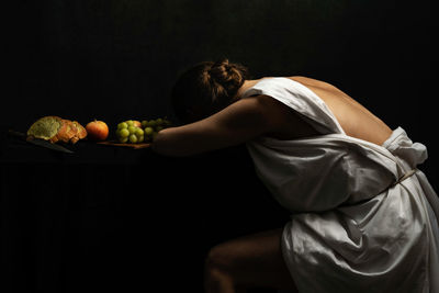 Midsection of woman sitting against black background