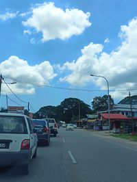 Vehicles on road against cloudy sky