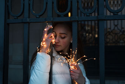 Young woman holding illuminated string light at night