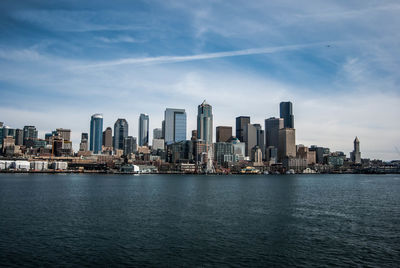 City at waterfront against cloudy sky