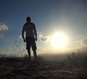 Full length rear view of silhouette man walking at sunset