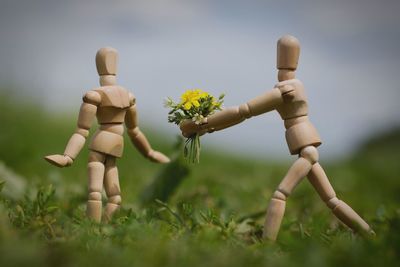 Close-up of wooden dolls with flowers on field