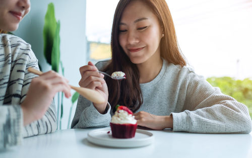 Two women enjoyed eating red velvet cup cake together