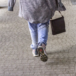 Low section of woman with bag walking on footpath