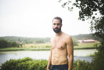 Portrait of young man standing against lake