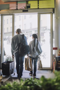 Full length rear view of father and daughter leaving at grocery store