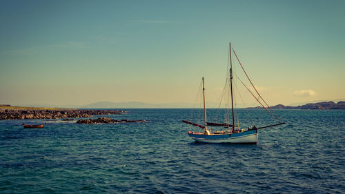 Sailboat sailing on sea against sky during sunset