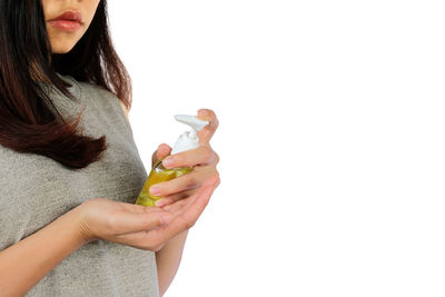 Midsection of woman holding leaf against white background