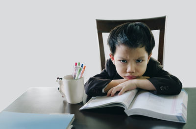 Portrait of boy reading book while sitting on table