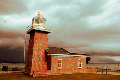 Lighthouse on field against sky