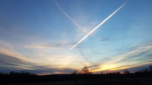 Vapor trails in sky at sunset