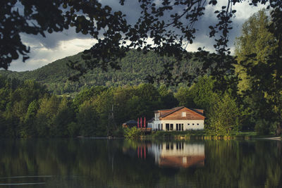 House by lake against sky