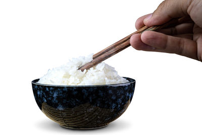 Close-up of hand holding bowl over white background