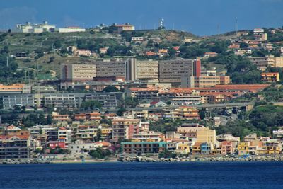 Aerial view of townscape by sea against sky