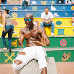 Full length portrait of shirtless man against wall