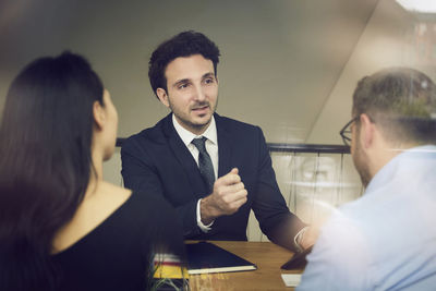 Confident young male financial advisor planning with customers at office