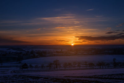 Scenic view of snow covered field against sky at sunset