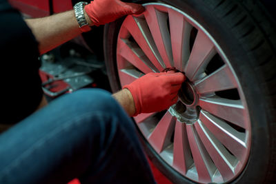Midsection of mechanic repairing car wheel